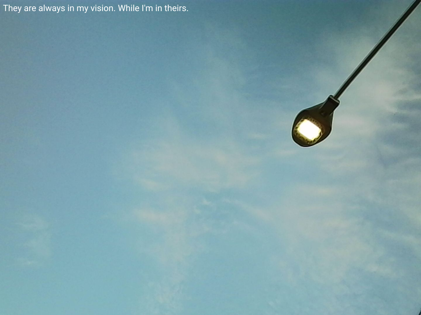 "They are always in my vision. While I'm in theirs." text reads as a glowing street lamp looms from the top right